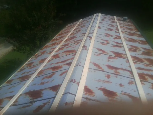 Rusted metal roof panels with new wood purlins before replacement — Storm Damage Roof Repair in Cary by Roofing Brothers