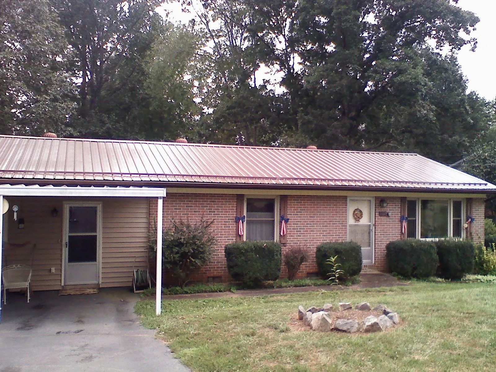 Bronze metal roof and carport on a brick ranch home — Roof Repair work by our crew in Cary